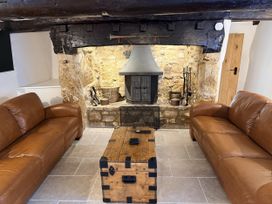 A living room with a fireplace and leather sofas at Bridge Cottage in Chideock