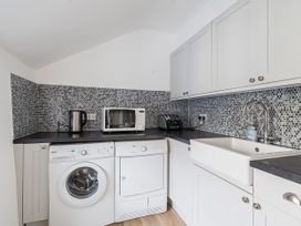 A kitchen with appliances including a washing machine and microwave at Bridge Cottage in Chideock
