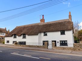 A thatched cottage with chimneys and windows at Bridge Cottage in Chideock