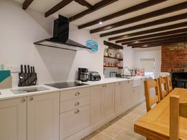 A kitchen with white cabinets and a wooden dining table at Bridge Cottage in Chideock