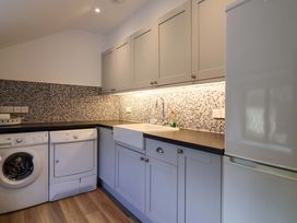 A laundry room with appliances and cabinets at Bridge Cottage in Chideock