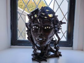 A sculpture of a face on a windowsill at Bridge Cottage in Chideock