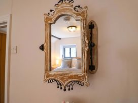 A mirror reflecting a bedroom with a bed and light at Bridge Cottage in Chideock