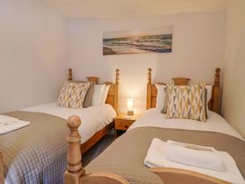 A bedroom with two beds and a lamp at Bridge Cottage in Chideock