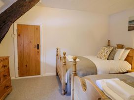 A bedroom with two beds and a wooden dresser at Bridge Cottage in Chideock