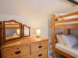 A bedroom with a bunk bed and a wooden dresser at Bridge Cottage in Chideock
