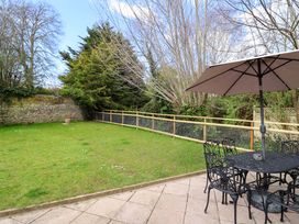 A garden with a table and chairs under an umbrella at Bridge Cottage in Chideock