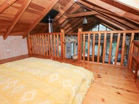 A loft with a bed and wooden railing at Cabin in Newport