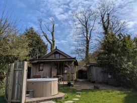 A hot tub and wooden cabin in a garden at Cosy Eco Cabin Cilgwyn near Newport, Pembrokeshire