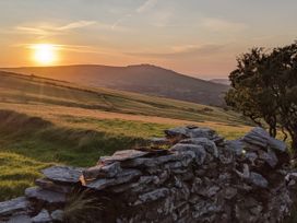 A sunset over hills and fields with a stone wall at Cosy Eco Cabin Cilgwyn near Newport, Pembrokeshire