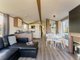 A living room with a sofa, table, and kitchen counter at Spruce Waterside Spa (Pet) Thirsk