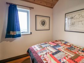 A bedroom with a quilted bed and framed art at The Faithfuls Cabin in Dingle