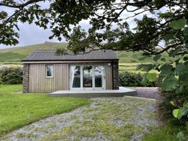 A cabin with a stone wall and sliding door at The Faithfuls Cabin in Dingle, County Kerry