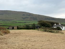A house and a shed in a field with a hill in the background at The Faithfuls Cabin in Dingle, County Kerry
