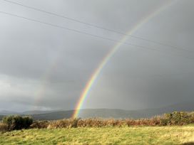 A rainbow in the sky with hills and clouds at The Faithfuls Cabin in Dingle, County Kerry