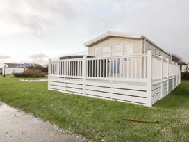 A mobile home with a deck and fence at Barney's Retreat in Newquay