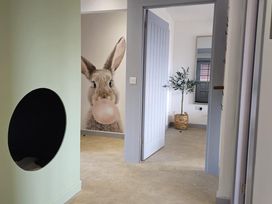 A hallway with a bunny wall art and potted plant at Kinder Lodge 3 (Pet) Portreath