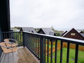 A balcony with chairs overlooking houses and a garden at Kinder Lodge 3 Spa (Pet) Redruth