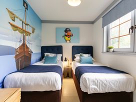 A bedroom with two beds and a pirate-themed wall mural at Kinder Lodge 3 Spa (Pet) Redruth