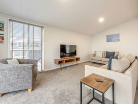 A living room with a sofa, armchair, coffee table, and television at Sonnet 2 Spa Roof Terrace (Pet) in Carmarthen