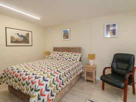 A bedroom with a bed and chair at Radharc an Hook @ Estuary Bliss