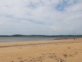 A beach with people walking along the shore at Radharc an Hook @ Estuary Bliss
