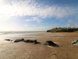 A beach with rock formations and houses on a cliff at Radharc an Hook @ Estuary Bliss