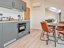A kitchen with cabinets, microwave, toaster, and dining table at Whalesborough Penthouse 2.0 in Marhamchurch