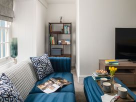 A living room with a blue sofa and bookshelves at Tides Door in Dartmouth
