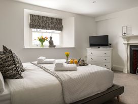 A bedroom with a bed, television, and flowers at Tides Door in Dartmouth