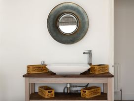 A sink with a mirror and wooden boxes in a bathroom at Tides Door in Dartmouth