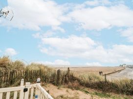A view of sand and sea with grass and a fence at 37 Redcar
