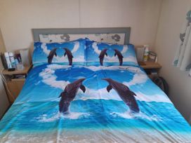 A bedroom with a bed covered in dolphin-themed bedding at Sands Retreat in Redcar