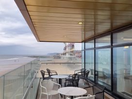 A balcony with tables and chairs overlooking the beach at Sands Retreat in Redcar