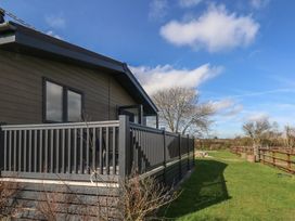 A house with a deck and fencing on a lawn at Grass Roots