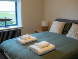 A bedroom with a bed and decorative items at The Joiners Cottage in Birling near Warkworth