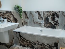 A bathroom with a bathtub and sink at The Joiners Cottage in Birling near Warkworth