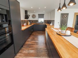 A kitchen with black cabinets and wood countertops at The Joiners Cottage in Birling near Warkworth