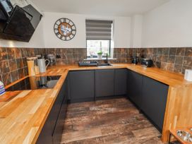 A kitchen with black cabinets and wooden countertop at The Joiners Cottage in Birling near Warkworth