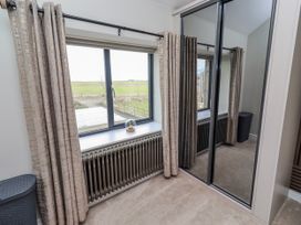 A bedroom with a window and mirror at The Joiners Cottage in Birling near Warkworth