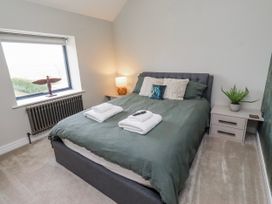 A bedroom with a bed, nightstand, and window at The Joiners Cottage in Birling near Warkworth