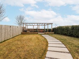 A garden with a path leading to a pergola at The Joiners Cottage Birling near Warkworth