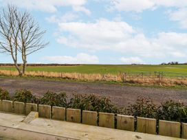 A view of a field with a tree and a gate at The Joiners Cottage in Birling near Warkworth