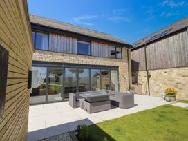 An outdoor seating area with a stone wall and glass doors at The Joiners Cottage in Birling near Warkworth