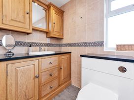 A bathroom featuring a mirror, sink, cabinet, and toilet at Oldfields