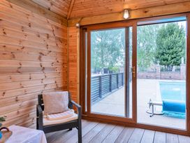 A snug with a chair and glass door opening to a pool at Oldfields