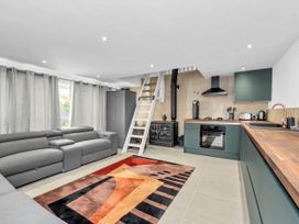 A living room with a sofa and kitchen area at Oldfields in Bury St Edmunds