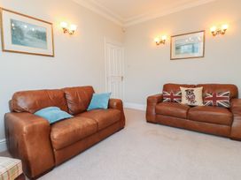 A living room with leather sofas and a painting at Bryniau in Pwllheli
