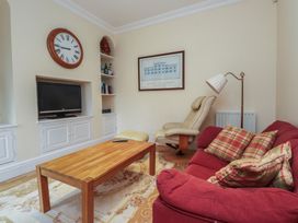 A living room with a sofa, table, and television at Bryniau in Pwllheli