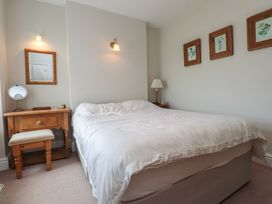 A bedroom with a bed, desk, lamp, and artwork at Bryniau in Pwllheli
